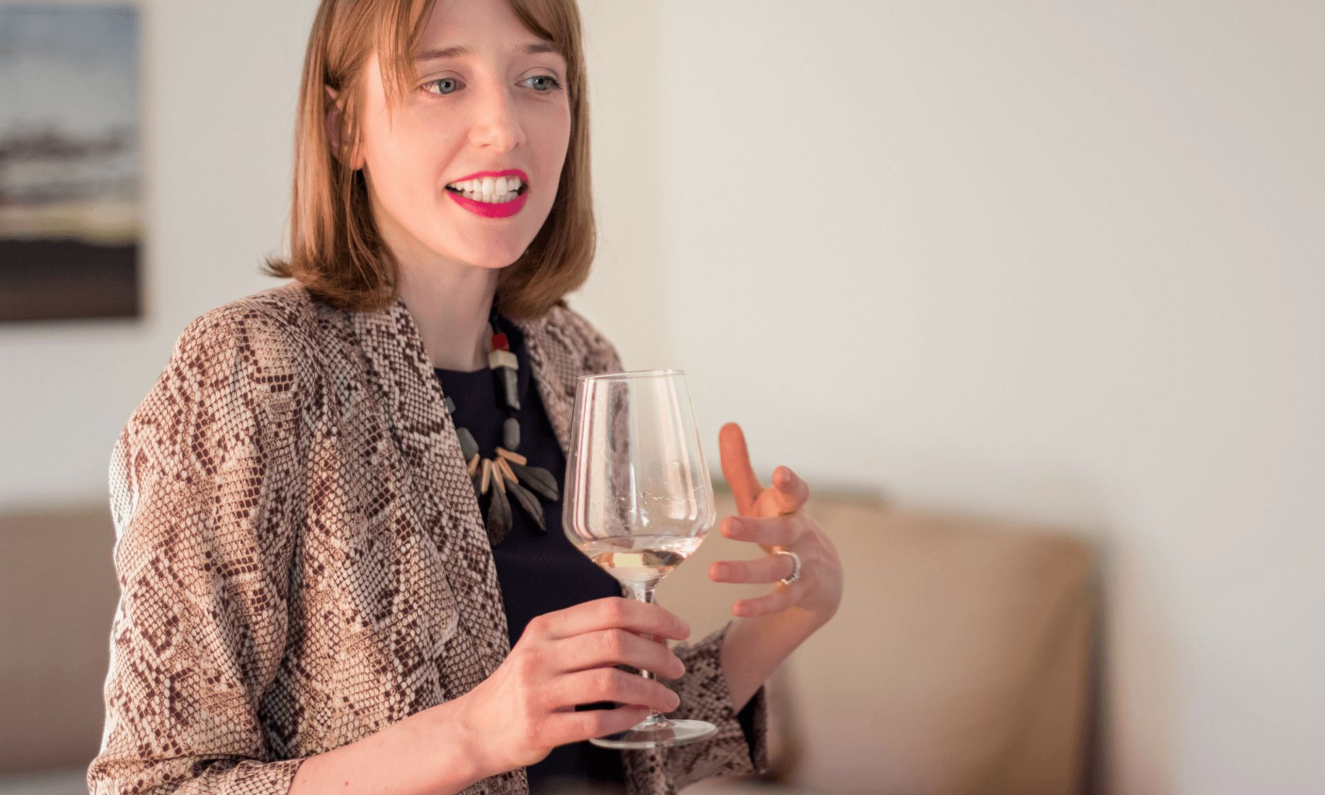 Anna holding a glass of white wine and expressing a thought at a tasting