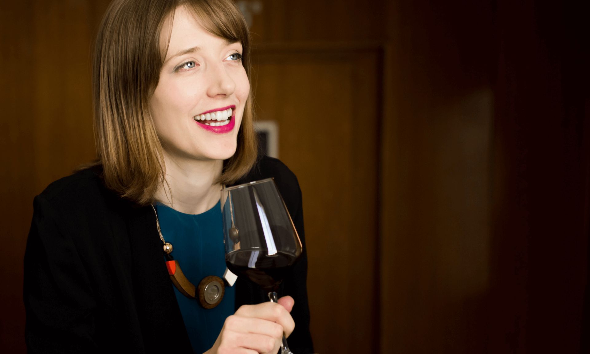 Anna holding a full wine glass and smiling
